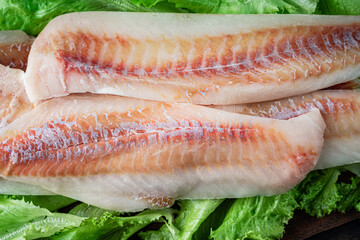 Fresh pollack fillet with cooking ingredients on a wooden cutting board. Top view.