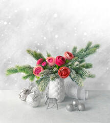 Festive winter flower arrangement with peonies and snow-covered fir branches in a vase on the table decorated for the holiday. Christmas or New Year concept