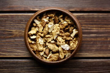Walnut seeds in bowl on wooden background