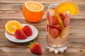 Glass of detox water with strawberry and orange on wooden background. Soft focus.