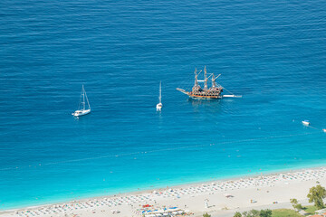 Aerial view of the resort beach and tourist ships and yachts in the blue sea lagoon. Vacation and coast in Turkey