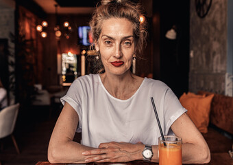Portrait of senior woman in casual wear sitting in coffee shop and looking at camera.