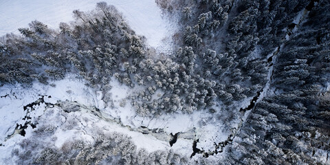 Flying over winter wonderland with frozen creeks and snow clothed trees. Shot with a drone in...