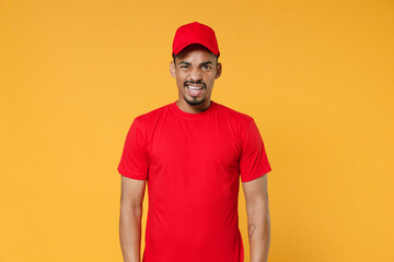 Delivery employee african man 20s in red cap blank print t-shirt uniform workwear work courier dealer service during quarantine coronavirus covid-19 virus concept isolated on yellow background studio.