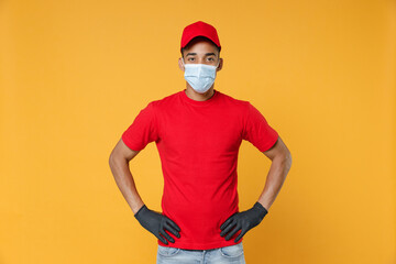 Delivery employee african man in red cap blank print t-shirt face mask gloves uniform work courier dealer service on quarantine coronavirus covid-19 virus concept isolated on yellow background studio.