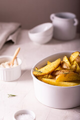 Slices of baked potatoes with rosemary and oil in a bowl