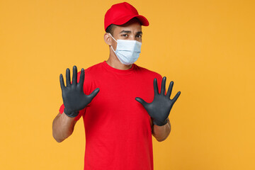 Delivery employee african man in red cap blank print t-shirt face mask gloves uniform work courier dealer service on quarantine coronavirus covid-19 virus concept isolated on yellow background studio.