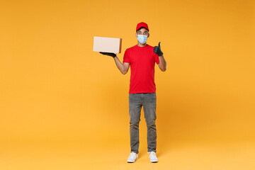 Full length delivery employee african man in red cap blank t-shirt face mask gloves work courier service on quarantine covid-19 virus concept hold cardboard box isolated on yellow background studio.