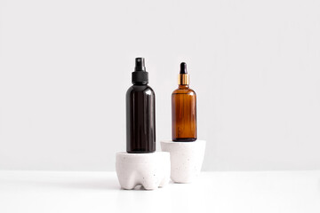 Serum, oil, acid, lotion in brown dropper glass and spray bottle on concrete pedestal side view with copy space. Spa products. Organic, bio, natural cosmetic. Beauty, skincare concept. Stock photo