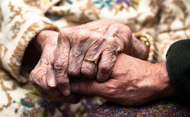 An isolated 95 year old caucasian female suffering from dementia welcomes the healing warmth of her son's hand reinforcing the power of touch in awakening communication.. 