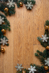 Christmas background with branches of spruce, golden baubles and shiny snowflakes, frame made of christmas tree branches