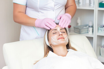 Fototapeta na wymiar cosmetology. young woman with receiving facial cleansing procedure in beauty salon.