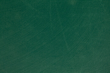 The textured surface of a green blackboard, with signs of deletion of chalk marks.
