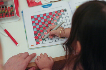 A boy doing a painting activity at his desk at home. He paints according to the instructions with a...