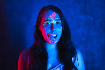 Portrait of calm young woman with UV body art. Beautiful fantastic drawing on naked skin.