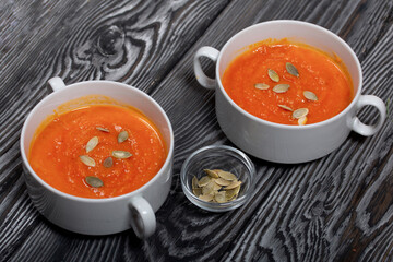 Pumpkin tomato cream soup. With the addition of pumpkin seeds. On pine boards.