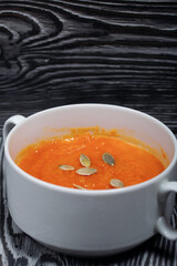 Pumpkin tomato cream soup. With the addition of pumpkin seeds. On pine boards.