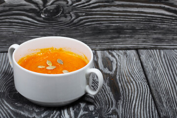 Pumpkin tomato cream soup. With the addition of pumpkin seeds. On pine boards.