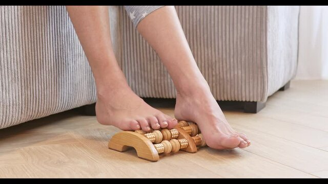 Foot massage. Women massage their aching feet with a wooden massager. Foot acupressure. 