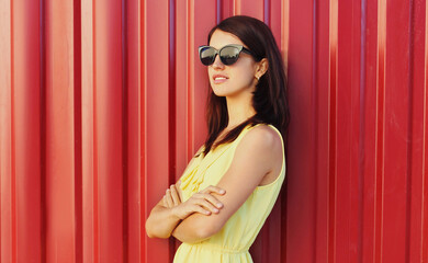 Fototapeta premium Portrait of beautiful young woman in yellow dress over a red background