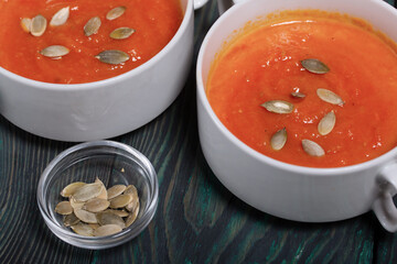 Pumpkin tomato cream soup. With the addition of pumpkin seeds. View from above. On pine boards.