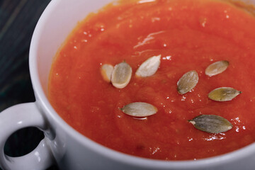 Pumpkin tomato cream soup. With the addition of pumpkin seeds. On pine boards.