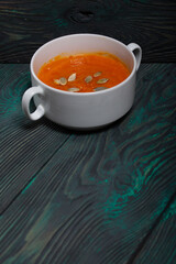 Pumpkin tomato cream soup. With the addition of pumpkin seeds. On pine boards.