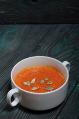 Pumpkin tomato cream soup. With the addition of pumpkin seeds. On pine boards.