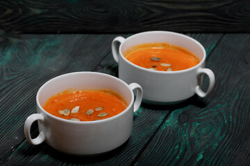 Pumpkin tomato cream soup. With the addition of pumpkin seeds. On pine boards.