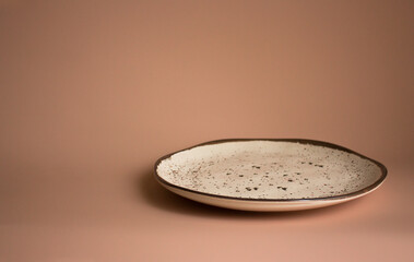 Empty ceramic plate with brown stains isolated on dusty pink background. Creative copyspace for overlay on product presentation, mockup, template, posters and wallpapers. Minimalism.