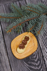 Eclairs with chocolate cream. Nearby is a spruce branch. On pine boards.