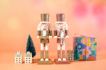 Bright modern Christmas scene with pink and gold wooden nutcracker ornaments, gifts and mini...