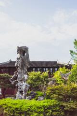 Giant rock in garden by Chinese architecture at Lingering Garden Scenic Area, Suzhou, Jiangsu, China