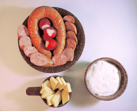 rown clay bowls with sausage, radish, cheese and sour cream on white background