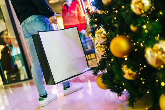 An unrecognizable person with a shopping bag in a mall at christmas