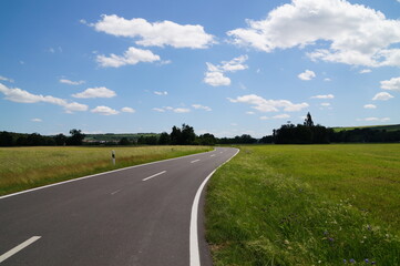 Fototapeta na wymiar paved road in a field in Germany on a Sunny summer day