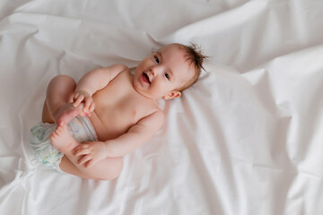 Baby boy 4 months lies on the bed with a white sheet, the view from above. space for text.