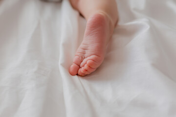 close-up of a child's bare feet lying on a bed covered with a white sheet