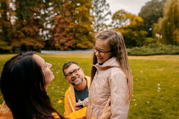 Family of three in raincoat enjoying together in city park after rain.