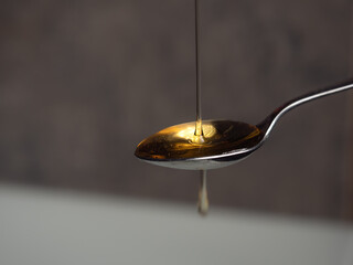 Liquid honey being poured onto a teaspoon