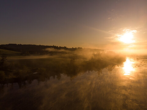 Misty lake with fog rises above the water at dawn. Autumn scenery. © Anton