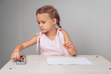 Portrait of a lovely young adorable child choosing from a pencil case of crayons and choosing what color to paint her picture on paper. Youth concept. photo with noise