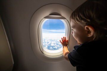 cute toddler points his finger at the sky through the window. first flight concept, traveling with children.