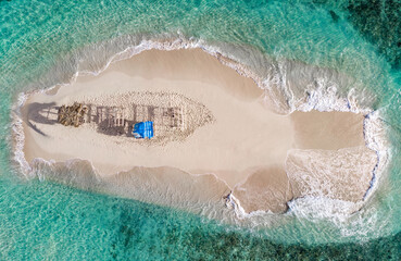 Aerial drone top down view of lone sand island with poor handmade gazebos and blue water lagoon of...