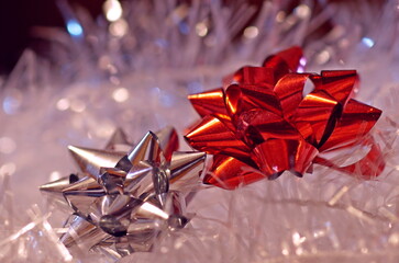 Closeup of red and silver gift bows on a white and luminous Christmas background