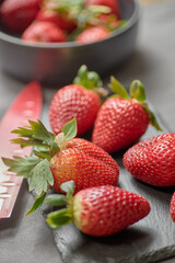 Fresh, clean strawberries ready to be sliced with a red knife.
