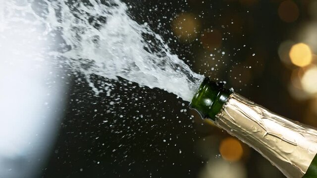 Super slow motion of Champagne explosion with flying cork closure, opening champagne bottle closeup.