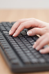 Close-up of hands typing on a keyboard in an office