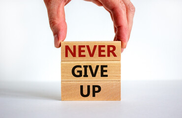 Never give up symbol. Male hand placing a block with word 'never' on top of a blocks tower with words 'never give up'. Beautiful white background. Copy space. Business and never give up concept.