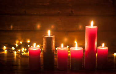 Lighted candles. Defocused Lights garlands in the background. On a dark background. Christmas card.